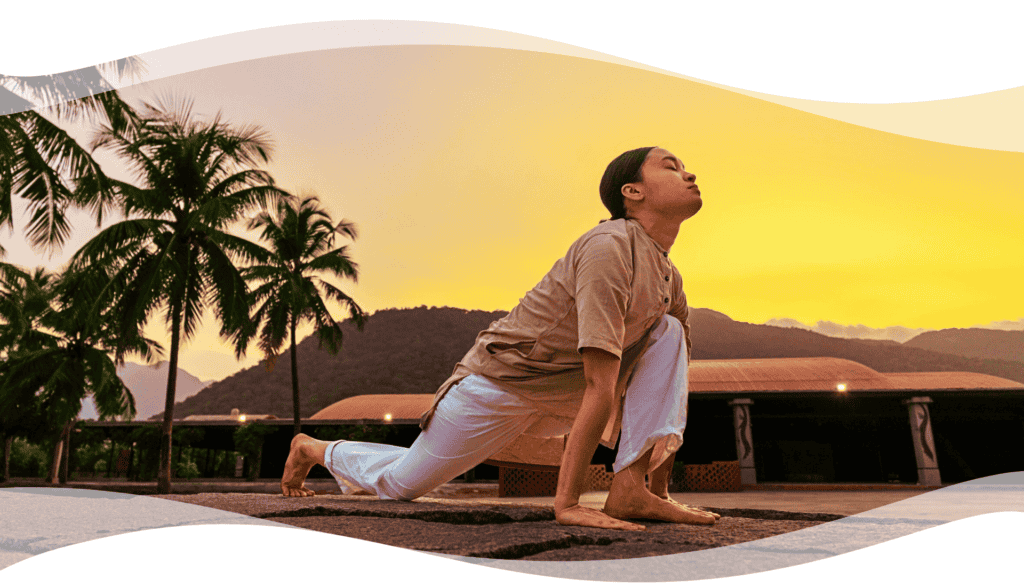 A practitioner performing Surya Kriya posture at sunrise amid palm trees and mountains, symbolizing energy, balance, and inner alignment through classical Hatha Yoga.