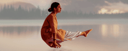 Woman practicing Angamardana by a calm lake, expressing lightness, strength, and balance through yogic movement