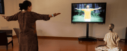 Participants practicing yoga indoors while following guided instruction on a screen in a calm studio setting.